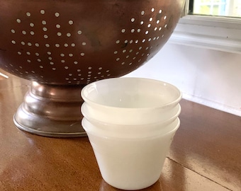 May include: A set of three white ceramic bowls stacked on top of each other. The bowls are round and have a smooth, glossy finish.
