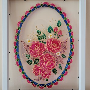 Peut inclure: Une œuvre d'art en vitrail encadrée représentant un bouquet de roses roses avec des feuilles vertes et des fleurs blanches. Les roses sont entourées d'une bordure décorative rose, bleue et verte.