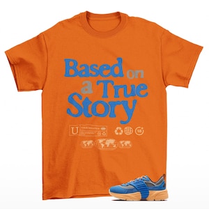 May include: An orange short-sleeve t-shirt featuring the blue text Based on a True Story, with smaller graphic icons including a globe and the number 18. A blue and orange athletic sneaker is positioned at the bottom right of the shirt.