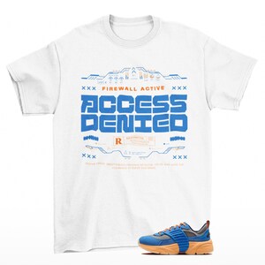 May include: A white short-sleeve t-shirt featuring a blue and orange graphic print that reads "FIREWALL ACTIVE" and "ACCESS DENIED" with technical interface elements. Below the shirt is a blue and orange sneaker with a thick rubber sole.