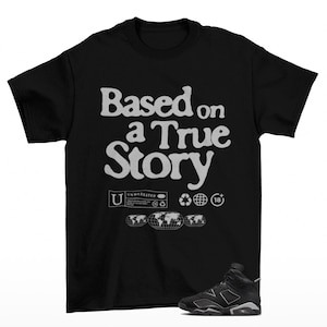 May include: Black t-shirt with the text "Based on a True Story" in white, along with graphic icons. A pair of black and gray sneakers is visible at the bottom right.