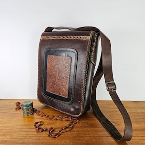 Cartera cruzada estilo sachel de cuero repujado VNTG. Correa con diseño geométrico estilo bohemio con hebilla en cuero grueso de grano completo. Interior de terciopelo