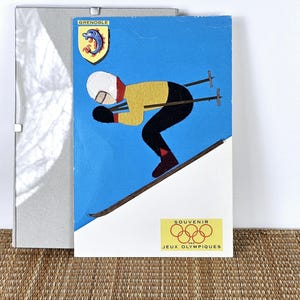 Carte postale vintage des Jeux olympiques de Grenoble par les Éditions d'Art E. Contensouzac - Skieur en feutre et techniques mixtes, souvenir des années 1960. Cadre clip en verre inclus