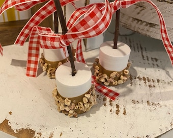 Set of three fake marshmallows dipped in caramel, nuts and a red and white gingham bow, fake food, gift