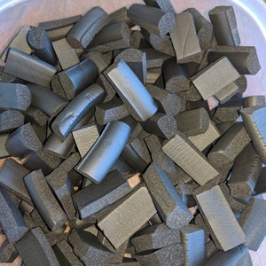 K&ouml;nnte beinhalten: Ein Beh&auml;lter gef&uuml;llt mit schwarzen Schaumgummi-St&uuml;cken in verschiedenen Formen und Gr&ouml;&szlig;en. Die St&uuml;cke sind alle auf eine &auml;hnliche L&auml;nge geschnitten und haben eine leicht abgerundete Kante.