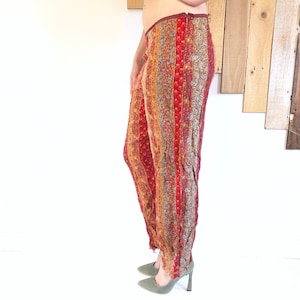 Könnte beinhalten: Rote, orange und braune gestreifte Hose mit Paisley-Muster. Die Hose hat eine weite Beinweite und einen ausgefransten Saum.