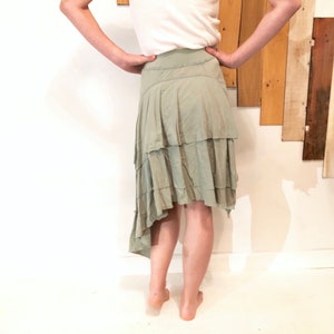 Könnte beinhalten: Ein hellgrüner, mehrlagiger Rock mit einem gekräuselten Saum. Der Rock ist asymmetrisch, eine Seite ist länger als die andere.