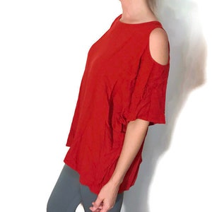 May include: A red cold shoulder top with short sleeves. The top is loose fitting and has a relaxed fit.