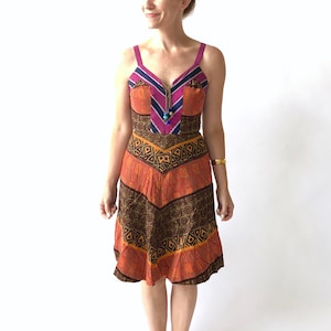 Könnte beinhalten: Ein ärmelloses Kleid mit V-Ausschnitt und einem farbenfrohen geometrischen Muster. Das Kleid hat eine braune, orange und rosa Farbgebung mit einem blauen Reißverschluss und Perlen.