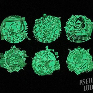 May include: Six round, green glow-in-the-dark pins with various spooky Halloween-themed illustrations. The pins feature a witch, a skeleton, a monster, a ghost, a vampire, and a creature with a skull face.