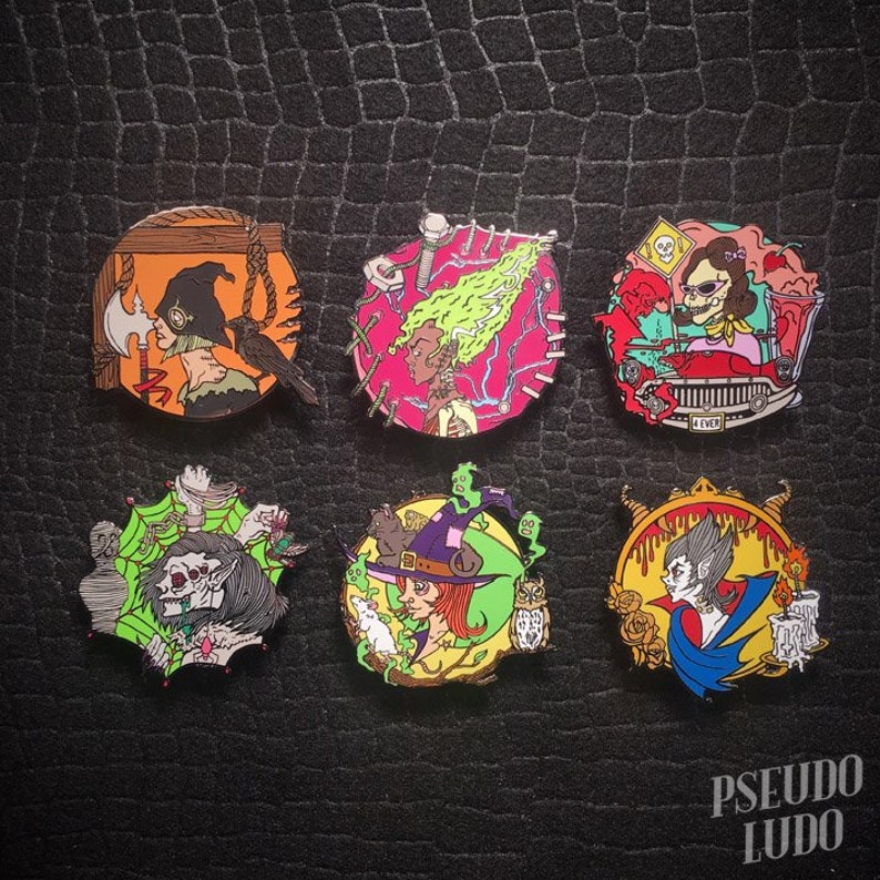 May include: Six enamel pins featuring various spooky characters. The pins are colorful and feature a witch, a vampire, a ghost, a creature with a spider web, a woman with a noose, and a woman driving a car. The pins are all circular and have a black outline.