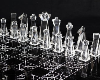 May include: A set of clear glass chess pieces on a black and white marble chessboard with a geometric pattern.