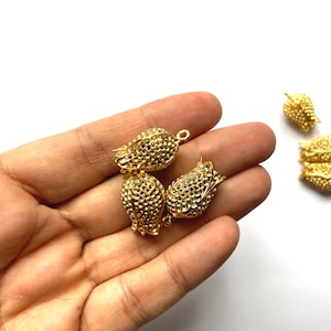 May include: Four gold-toned metal flower-shaped charms with a textured surface. The charms have a loop at the top for attaching to jewellery or other crafts.