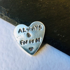 May include: A silver heart-shaped charm with the words "ALWAYS & For ever" engraved on it.