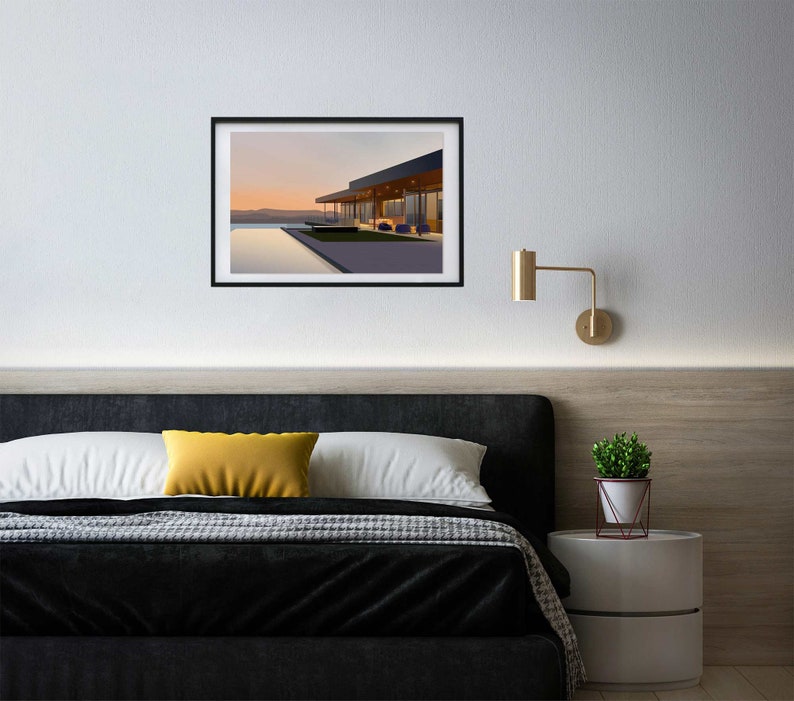 May include: A framed photograph of a modern house with a swimming pool and a view of a sunset. The house has large windows and a patio with chairs. The photo is hanging on a white wall above a black headboard.