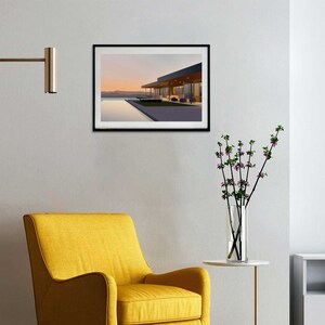 May include: A framed print of a modern house with a pool and a view of the sunset. The house has a flat roof and large windows. The pool is rectangular and surrounded by a concrete deck. The sunset is in the background and is a soft pink and orange color.
