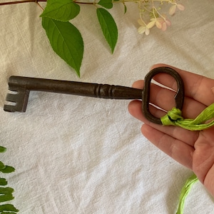 May include: A large, antique-looking metal key with a decorative handle. The key is tied with a green ribbon.