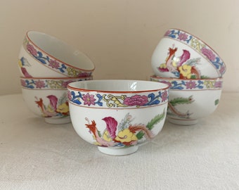 May include: Set of six white porcelain bowls with a colorful floral and bird design. The bowls have a red, yellow, blue, and pink floral pattern with a bird design in the center.