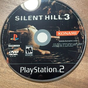 May include: A black PlayStation 2 DVD game disc for Silent Hill 3. The disc has white text and a graphic of a figure. The game title and the PlayStation 2 logo are visible. The disc also features the Konami logo.