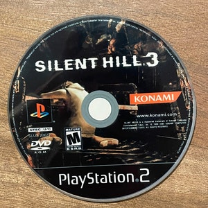 May include: A black DVD-ROM disc for the PlayStation 2 console. The disc features the game title "SILENT HILL 3" in white lettering, the Konami logo, and the PlayStation 2 logo. The disc is rated "M" for Mature.
