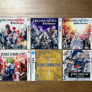 May include: Six Nintendo 3DS video game cases are displayed. The games include "Fire Emblem Fates: Birthright", "Fire Emblem Fates: Conquest", "Fire Emblem Fates: Revelation", "Fire Emblem Echoes: Shadows of Valentia", "Fire Emblem: Shadow Dragon", and "Fire Emblem: Awakening".