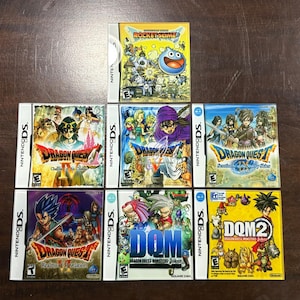 May include: A collection of Nintendo DS video game cases, featuring titles like "Dragon Quest" and "Rocket Slime." The game covers display colorful illustrations of characters and game titles. The cases are arranged on a brown surface.