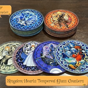 May include: Kingdom Hearts tempered glass coasters, 3.9 inches in diameter. The coasters feature colorful stained-glass designs with various characters. The coasters are round and stacked in multiple piles, with a dark brown surface in the background.