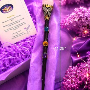 K&ouml;nnte beinhalten: Ein schwarzer Zauberstab mit einer rosafarbenen Kugel an der Spitze, einem silbernen Schmetterlingsakzent und drei eingebetteten Steinen in Blau, Gelb und Violett. Der Stab ist 11,25 Zoll lang und 1,25 Zoll breit, inklusive einer Dankeskarte.