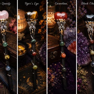 K&ouml;nnte beinhalten: Vier Zauberst&auml;be mit herzf&ouml;rmigen Edelsteinen an der Spitze, beschriftet mit Rose Quartz, Tiger's Eye, Carnelian und Black Obsidian. Jeder Stab hat einen silberfarbenen Schmetterling unter dem Herz und drei kleine Perlen am schwarzen Schaft.