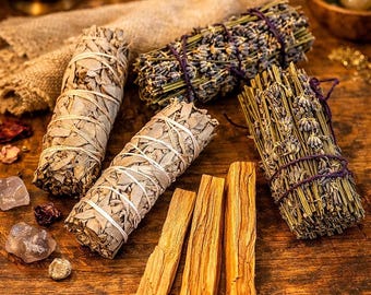 May include: An assortment of natural incense bundles and sticks arranged on a wooden surface. The image features white sage bundles, lavender bundles, and palo santo sticks. Additional elements include candles, crystals, and a small wooden bowl.