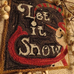 May include: A black and red wool rug with the words "Let It Snow" in white yarn. The rug has a gold border and is decorated with a snowman.