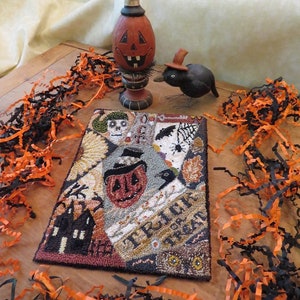 May include: A Halloween-themed needlepoint rug with a black and orange color scheme. The rug features a variety of Halloween imagery, including a pumpkin, a black cat, a haunted house, and the words "Trick or Treat".