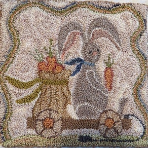 May include: A brown and gray bunny rabbit pulling a wagon full of carrots. The wagon has wheels and a brown wooden bed. The bunny is sitting in the wagon and pulling it with its front paws. The background is a light brown color.