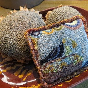 May include: A brown ceramic plate with a blue and brown patterned pillow and two dried sunflowers on top.