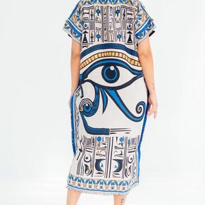 May include: A white and blue caftan dress featuring an Egyptian eye design. The dress has short sleeves and a fringed hem. The text "KEHOT" and "Every thread holds quality" is visible at the top left.