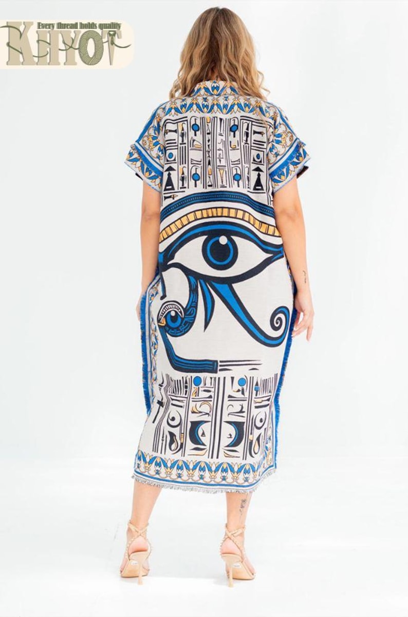 May include: A white and blue caftan dress featuring an Egyptian eye design. The dress has short sleeves and a fringed hem. The text "KEHOT" and "Every thread holds quality" is visible at the top left.