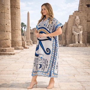 Full-length photo of model wearing short-sleeved caftan with split hem and tribal Egyptian pattern.