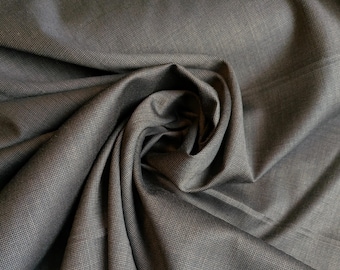 May include: Close-up of a dark gray fabric with a subtle woven texture. The fabric is draped and folded, creating shadows and highlights that emphasize its texture and depth. The material appears to be smooth and possibly suitable for clothing or upholstery.