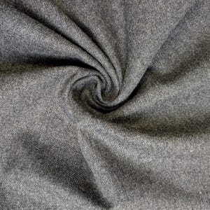 May include: Close-up of a swatch of gray fabric with a textured surface. The fabric is folded and swirled, creating shadows and highlights. The material appears to be a medium-weight textile, suitable for apparel or home decor projects.