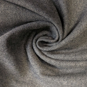 May include: Close-up of a swatch of gray fabric with a soft, textured surface. The fabric is draped in a swirling pattern, creating shadows and highlights. The material appears to be a medium-weight textile.