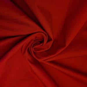 May include: A solid deep red fabric with a visible diagonal twill weave pattern. The material is gathered into a central swirl, creating soft folds and shadows that highlight the texture and the consistent, vibrant red color throughout.