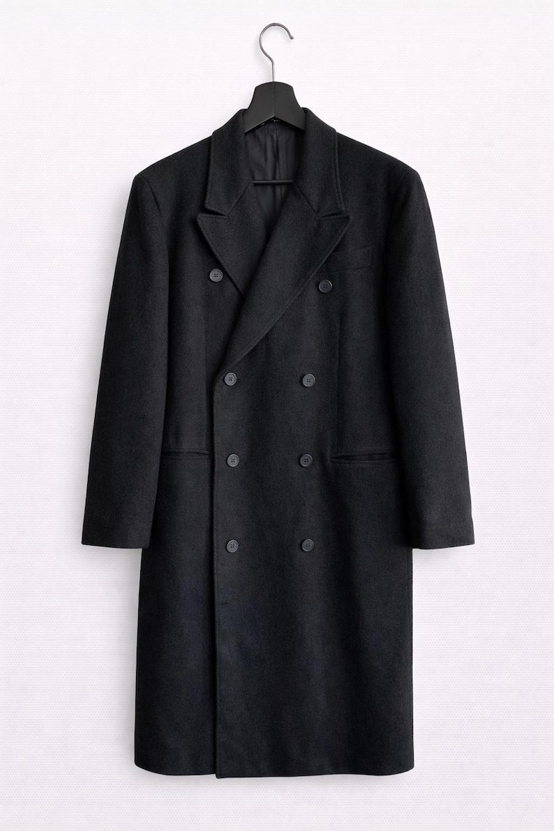 May include: A black double-breasted overcoat with six buttons and a notched lapel, hanging on a black hanger. The coat has two front pockets and a classic, tailored design. The coat is made of a dark, solid-colored fabric.