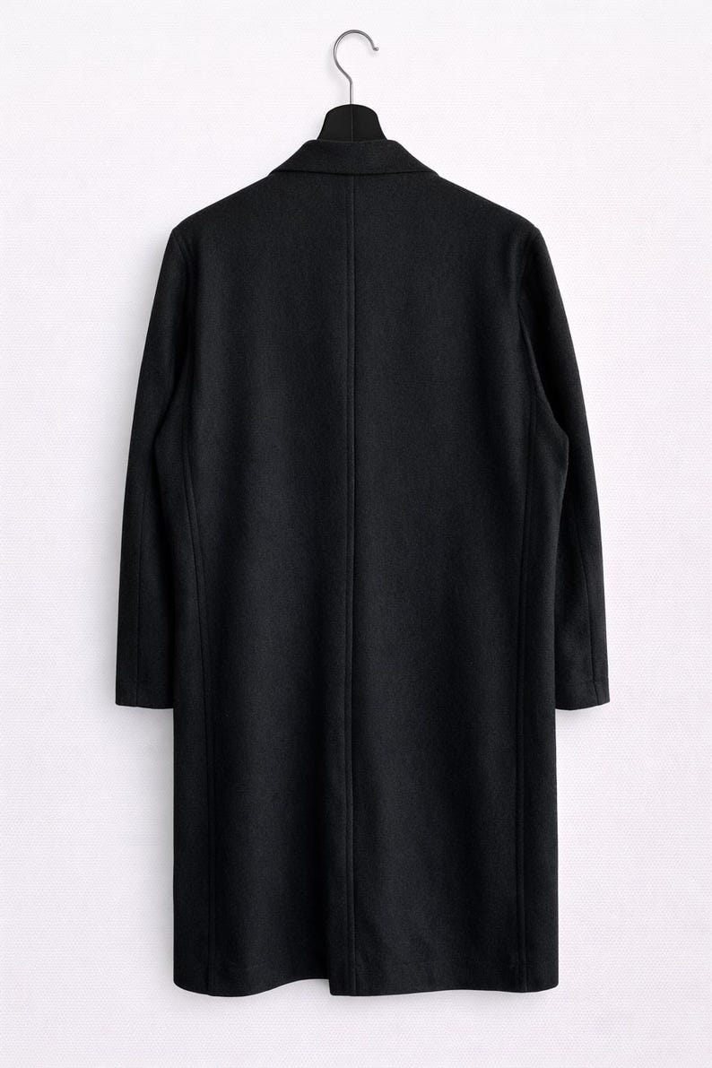 May include: A long, black coat hanging on a black hanger against a white background. The coat has a classic design with a notched collar and a single vent in the back. The coat's length extends to the mid-calf.