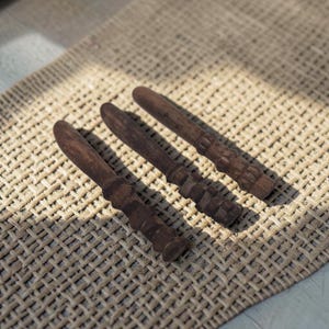 May include: Three dark brown wooden spreaders with smooth, rounded blades and textured, segmented handles. Each utensil features a consistent dark wood grain finish, a flat spreading edge, and a grip area composed of several carved, rounded sections.