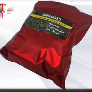 May include: A red pouch with a label that reads "Shungit El mineral de la nueva Era Mineral Purificador del Agua".
