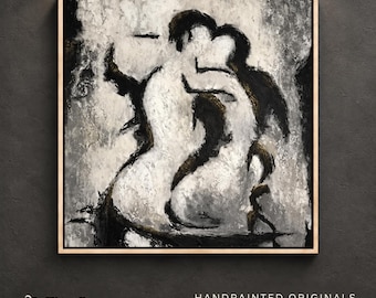 May include: A square canvas painting in a light wood frame featuring an abstract black, white, and gray depiction of two figures embracing. The artwork uses thick, textured brushstrokes to define the silhouettes against a mottled background.