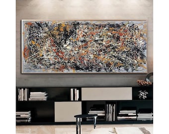 May include: Abstract painting with black, white, yellow, and orange paint strokes on a gray canvas. The painting is framed in a light wood frame.