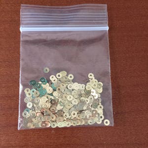 May include: A clear plastic bag filled with gold-colored round sequins.