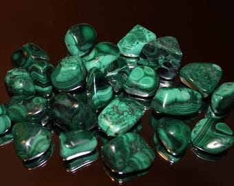 May include: A collection of green malachite tumbled stones. The stones are smooth and polished, with a variety of shapes and sizes.