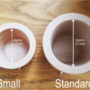 May include: Two white ceramic pots, one labeled "Small" and the other "Standard". The small pot measures approximately 2.5 inches in diameter, while the standard pot measures approximately 3.5 inches in diameter.